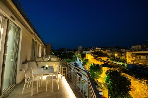 a balcony with a table and chairs at night at SKIA luxury living above the walls in Thessaloniki