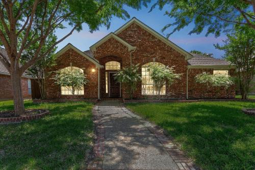 a brick house with a tree in the yard at Family Fun Retreat- Pool & Entertainment Haven! home in Frisco