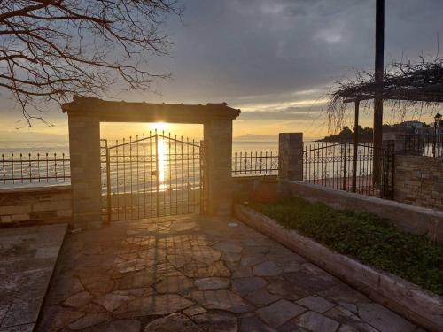 a gate with the sun setting over the ocean at Homico 1 Lefokastro in Lefokastro