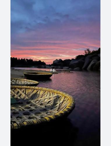 a group of boats sitting in the water at sunset at Anu Paradise Hampi in Hampi