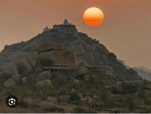 an orange sun sitting on top of a mountain at Anu Paradise Hampi in Hampi