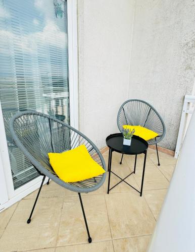 two chairs and a table with yellow pillows on a balcony at Apartman Latice in Tomislavgrad