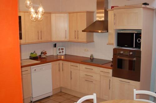 une cuisine avec des armoires en bois et un four à plaques de cuisson dans l'établissement Chambre privée chez l'hôte, à Tourcoing