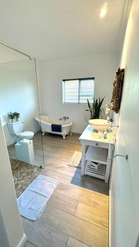 a bathroom with a tub and a toilet and a sink at Plett57 - Self Catering - Room No2 in Plettenberg Bay