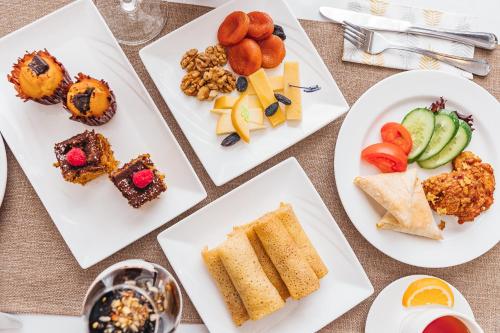 four white plates with different types of food on them at Grand Fergana Hotel in Fergana
