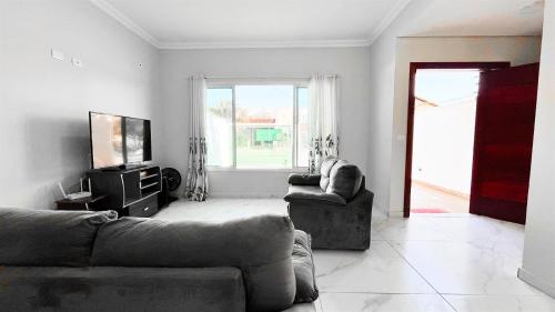 a living room with two couches and a television at Triplex com piscina e área gourmet in Guaratuba
