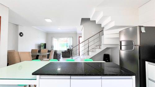 a kitchen with a refrigerator and a table with chairs at Triplex com piscina e área gourmet in Guaratuba
