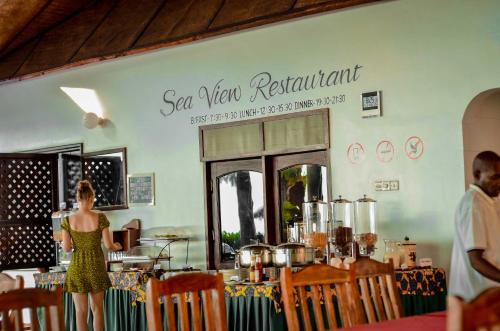 een vrouw die voor een balie staat in een restaurant bij Mnarani Beach Cottages in Nungwi