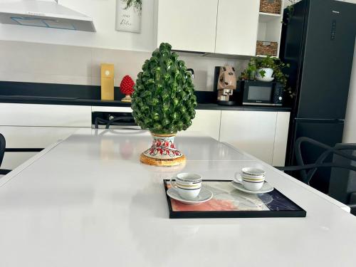 a table with two cups and a plant on it at Elsa Holiday Home in Fontane Bianche