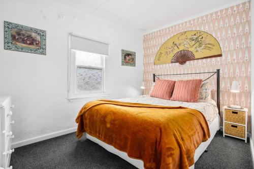 ein Schlafzimmer mit einem Bett mit einer orangefarbenen Decke in der Unterkunft Croft Cottage in Hepburn Springs