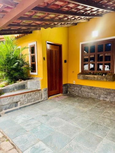 a yellow house with a door and a patio at Casa incrível praia dos anjos in Arraial do Cabo