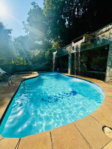 a swimming pool with a waterfall in a yard at Casa incrível praia dos anjos in Arraial do Cabo