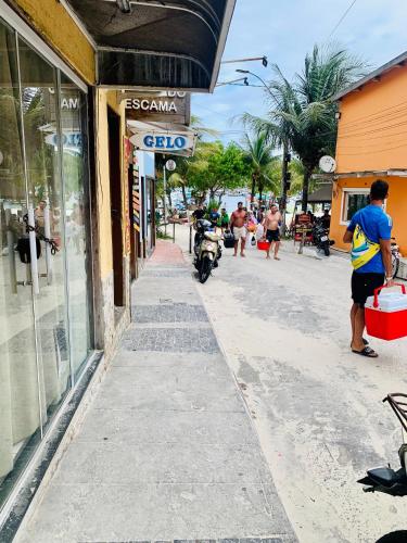 a man walking down a street next to a store at Casa incrível praia dos anjos in Arraial do Cabo