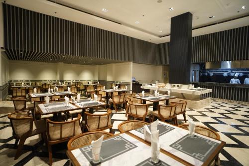 a restaurant with tables and chairs in a room at Hotel SOOT in Kolkata