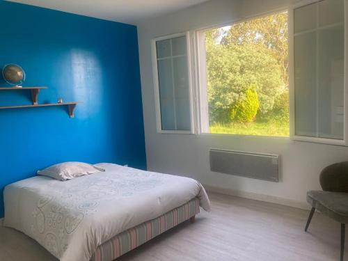 a blue bedroom with a bed and a window at La campagne proche de l Océan in Saint-Gervais