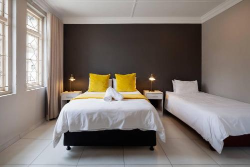 a bedroom with two beds with yellow pillows at Farquhar Lodge in Ladysmith