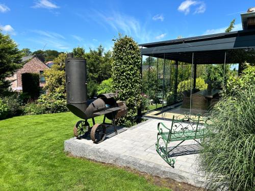 a barbecue grill and a bench in a yard at La Maison de Rose in Riemst