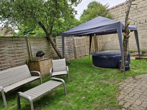 a gazebo with two chairs and a bench in a yard at Maison avec jardin, jacuzzi entre Paris et Disney in Champigny-sur-Marne