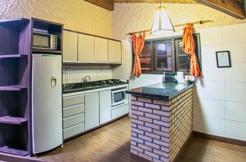 a kitchen with a white refrigerator and a counter at Pousada Bangalôs do Rosa in Praia do Rosa