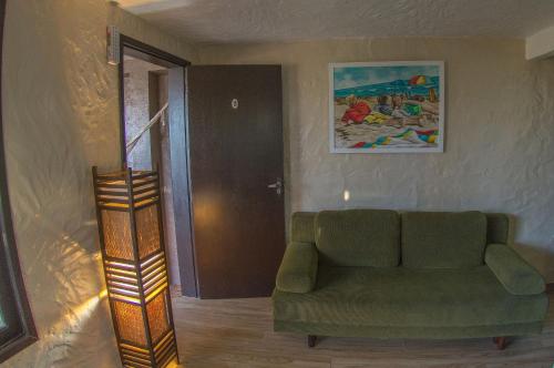 a living room with a green couch and a painting at Pousada Bangalôs do Rosa in Praia do Rosa