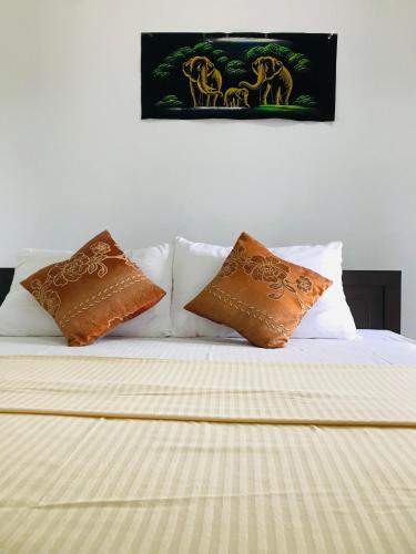 a bed with brown and white pillows on it at The Velvet Dambulla in Dambulla