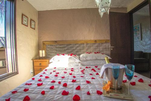 a bedroom with a bed with red roses on it at Pousada Bangalôs do Rosa in Praia do Rosa