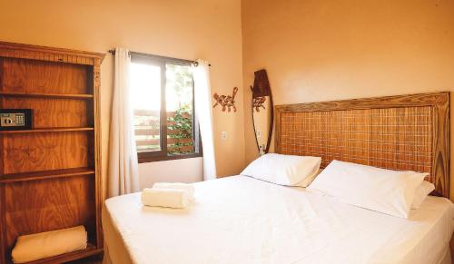 a bedroom with a white bed with a window at Pousada Bangalôs do Rosa in Praia do Rosa