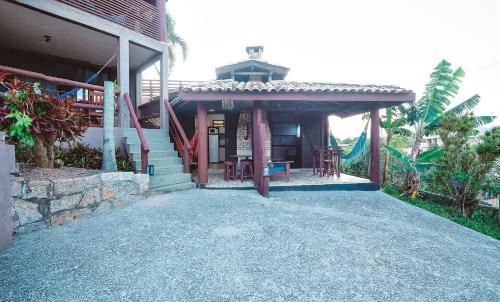 a house with a porch with a table and chairs at Pousada Bangalôs do Rosa in Praia do Rosa