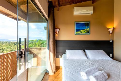 a bedroom with a bed and a large window at Pousada Bangalôs do Rosa in Praia do Rosa