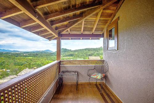 a balcony with a bench and a view of the mountains at Pousada Bangalôs do Rosa in Praia do Rosa