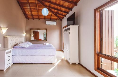 a bedroom with a bed and a mirror and a window at Pousada Bangalôs do Rosa in Praia do Rosa