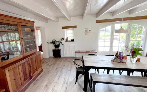 a dining room with a table and chairs and windows at Havre de paix à proximité de l'océan in Plonéour-Lanvern