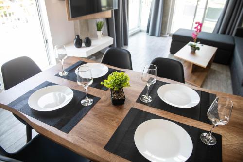 a wooden table with white plates and wine glasses at SKIA luxury living above the walls in Thessaloniki