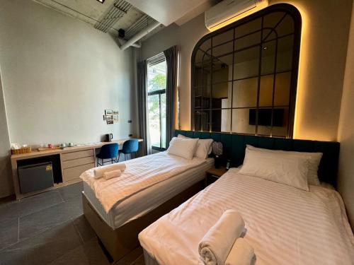 a bedroom with two beds and a mirror at Chainam-Charmchuree residences cafe and spa in Ban Bang Bua Thong