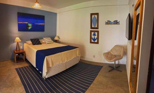 a bedroom with a bed and a chair in it at Suítes Arraial in Arraial d'Ajuda