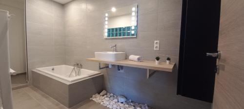 une salle de bain avec un lavabo et une baignoire dans l'établissement Luxueux appartement dans propriété contemporaine, jardin privatif, piscine, à La Roquette-sur-Siagne
