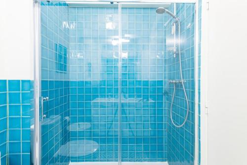 a blue tiled bathroom with a shower and two toilets at Casa do Pátio in Figueira da Foz