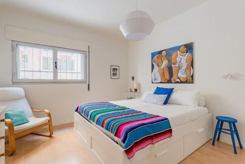 a white bedroom with a bed and a chair at Casa do Pátio in Figueira da Foz