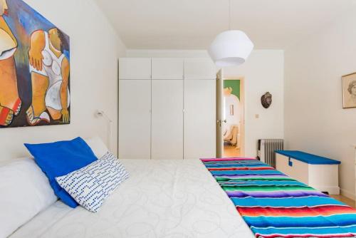 a bedroom with a white bed and a painting on the wall at Casa do Pátio in Figueira da Foz
