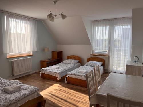 a room with three beds and a table and windows at SKiPER Dębki in Dębki