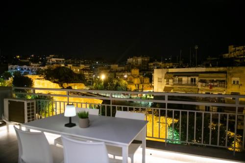 a white table and chairs on a balcony at night at SKIA luxury living above the walls in Thessaloniki
