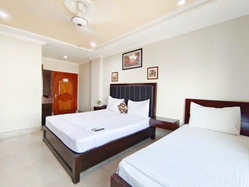 a bedroom with two beds and a cat sitting on it at Hotel Crown Inn Multan in Multan