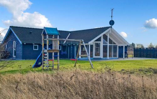 a blue house with a playground in front of it at Holiday Home Ankersholm Rødby Ii in Rødby