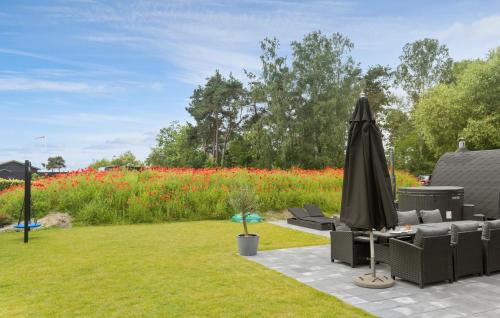 a patio with an umbrella and a field of flowers at Amazing Home In Ebeltoft With Kitchen in Ebeltoft