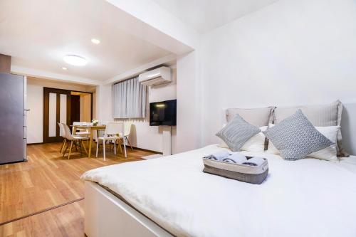 a bedroom with a large white bed and a dining room at Charming Guesthouse in the Heart of Okubo 丶Steps to Metro and Convenient Travel! EoW4 in Tokyo