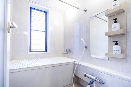 a white bathroom with a sink and a mirror at Charming Guesthouse in the Heart of Okubo 丶Steps to Metro and Convenient Travel! EoW4 in Tokyo