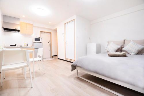 a white bedroom with a bed and a kitchen at CG Charming Guesthouse in the Heart of Okubo 丶Steps to Metro and Convenient Travel! YoE4 in Tokyo