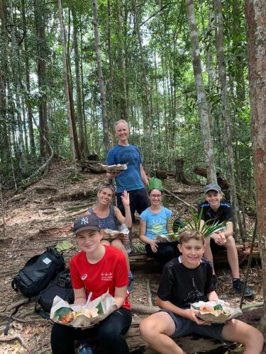 a group of people sitting on a trail in the woods at Wisma Batu Mandi in Bukit Lawang