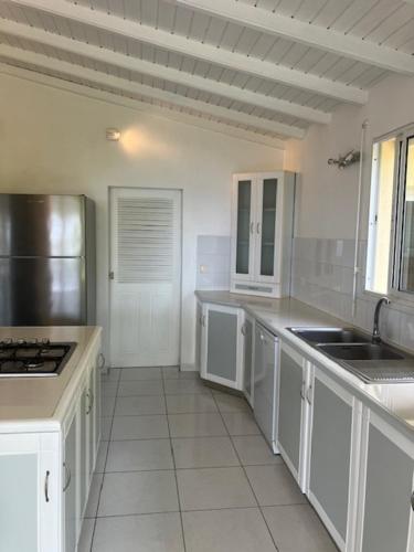 a large kitchen with white cabinets and a refrigerator at Villa Bleu Horizon in Bouillante