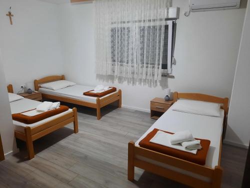 a room with three beds and a window at Rooms Vidović in Međugorje